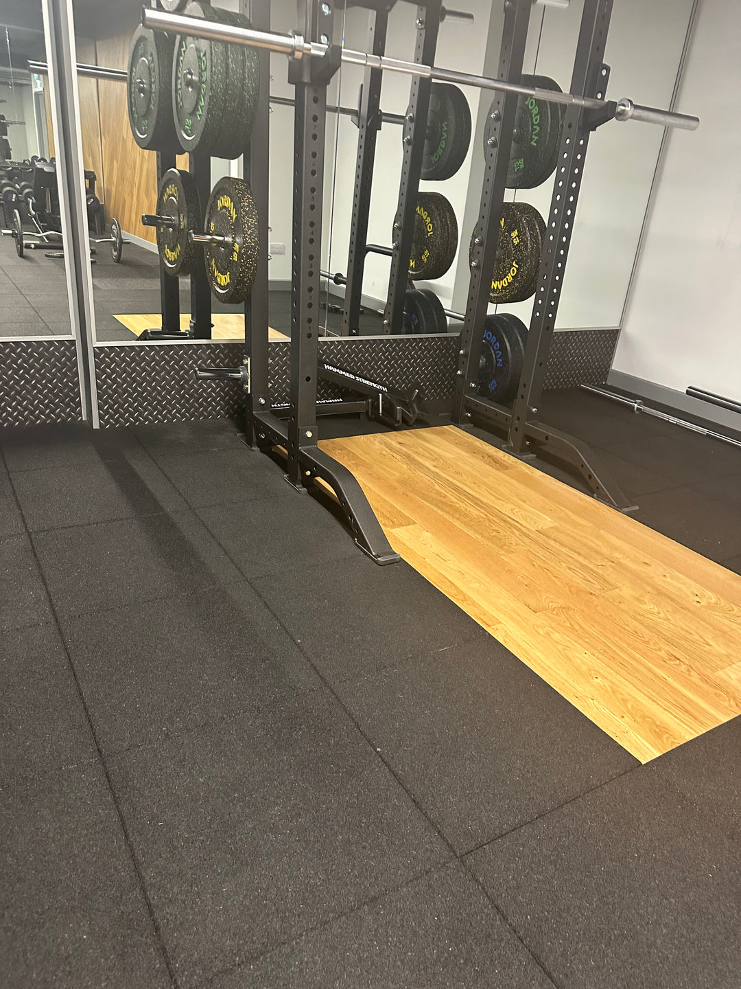 SilentTile 30mm Acoustic Gym Flooring Fitness Interlocking Tile on a gym's lifting platform, featuring a power rack with bumper plates, designed for soundproofing, noise reduction, and vibration damping in fitness environments.